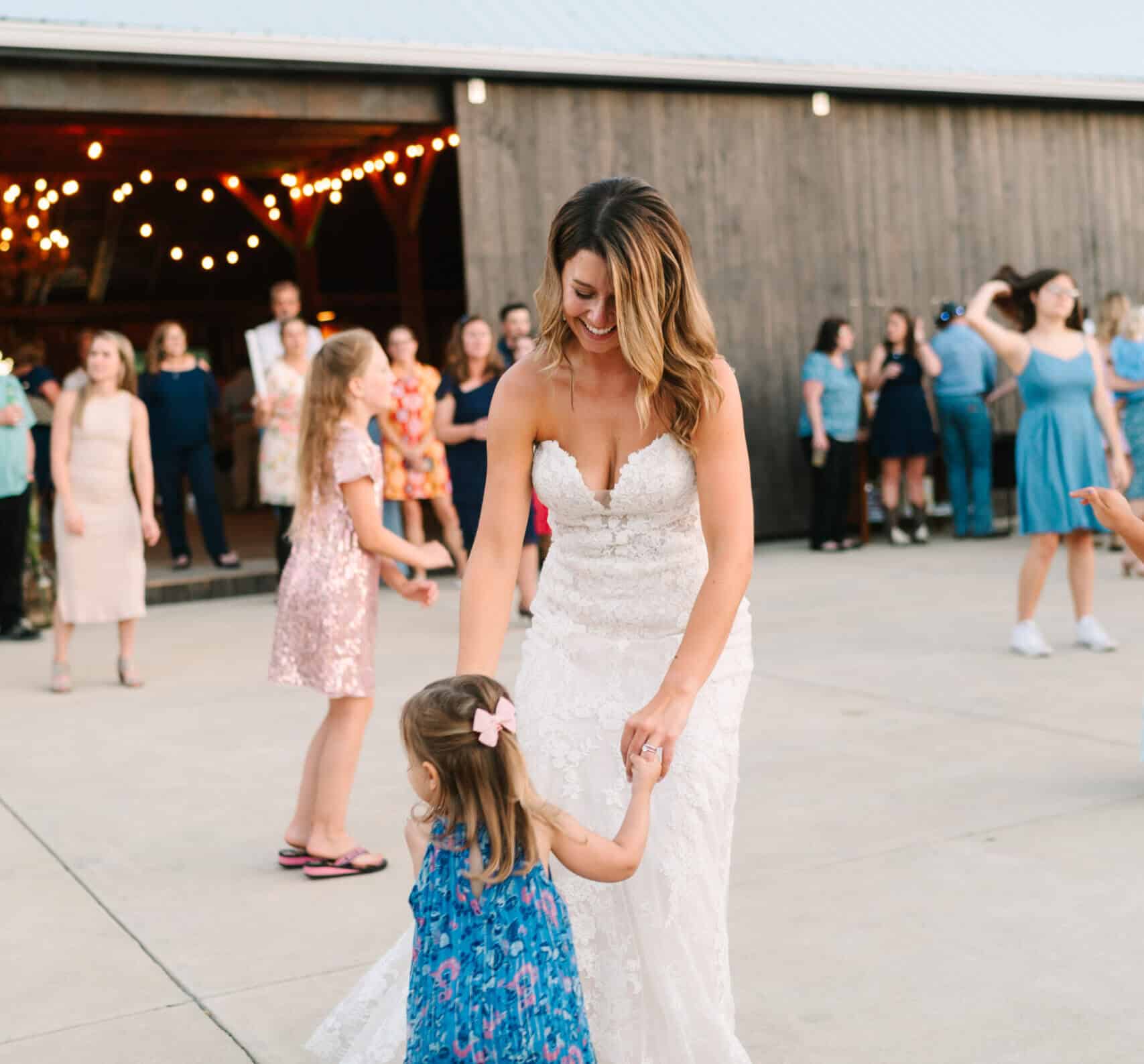 Bride dancing with a young child on the patio outside the barn during a wedding reception at Canaan Springs, a Northern Virginia wedding venue near Winchester