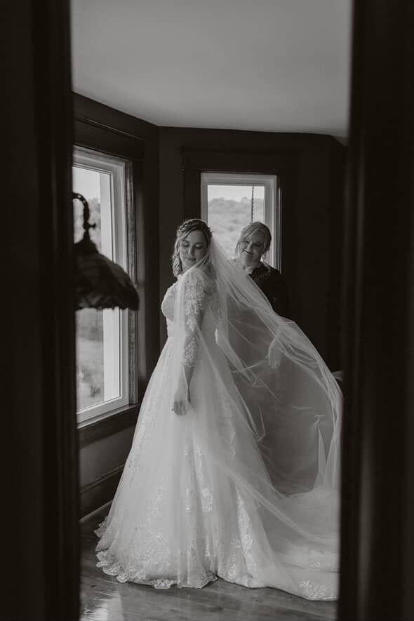 Bride posing by the window in the farmhouse Airbnb at Canaan Springs while her mom adjusts her veil, capturing a tender pre-wedding moment at this Northern Virginia farm wedding venue
