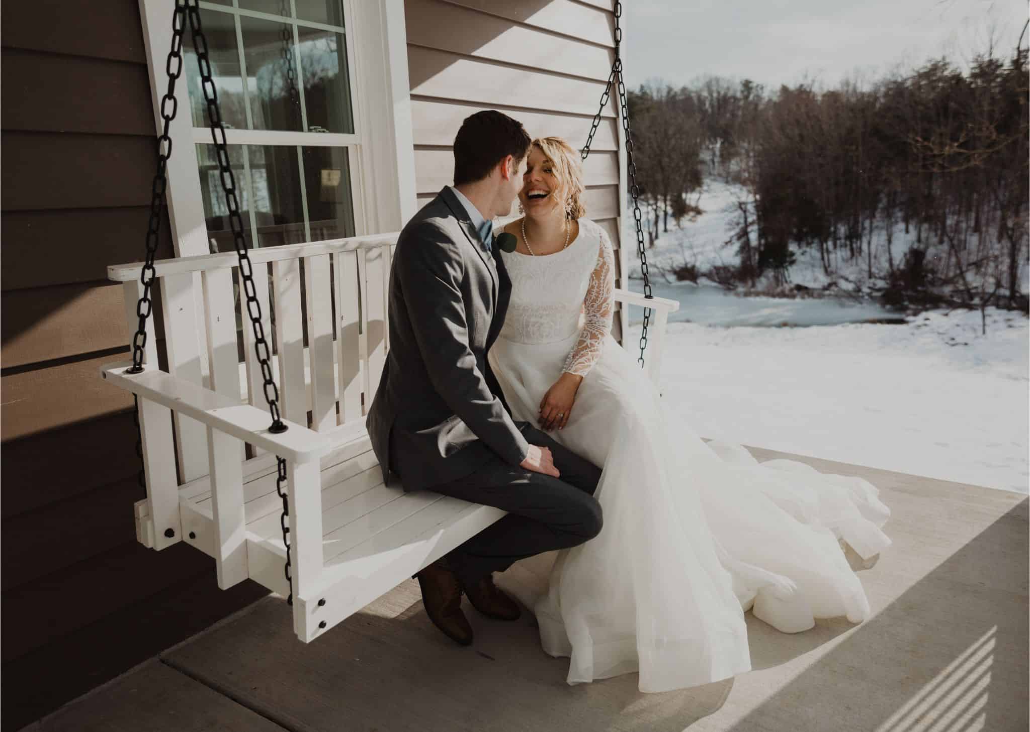 Just married couple laughing on the iconic porch swing at Canaan Springs, a rustic Northern Virginia farm wedding venue near Winchester, VA