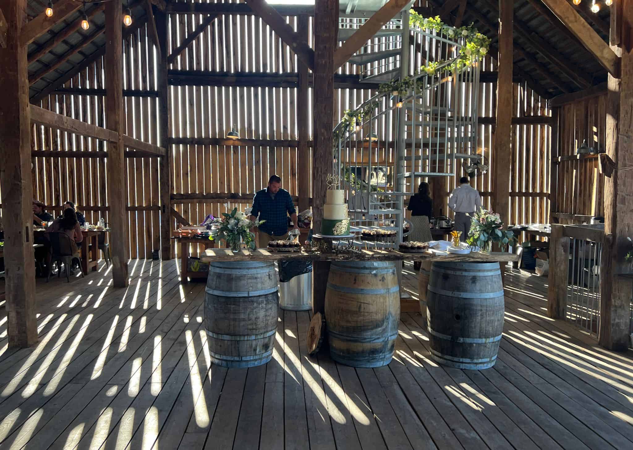 Barn interior at Canaan Springs decorated for a wedding reception featuring rustic whiskey barrels, part of the Northern Virginia farm wedding venue