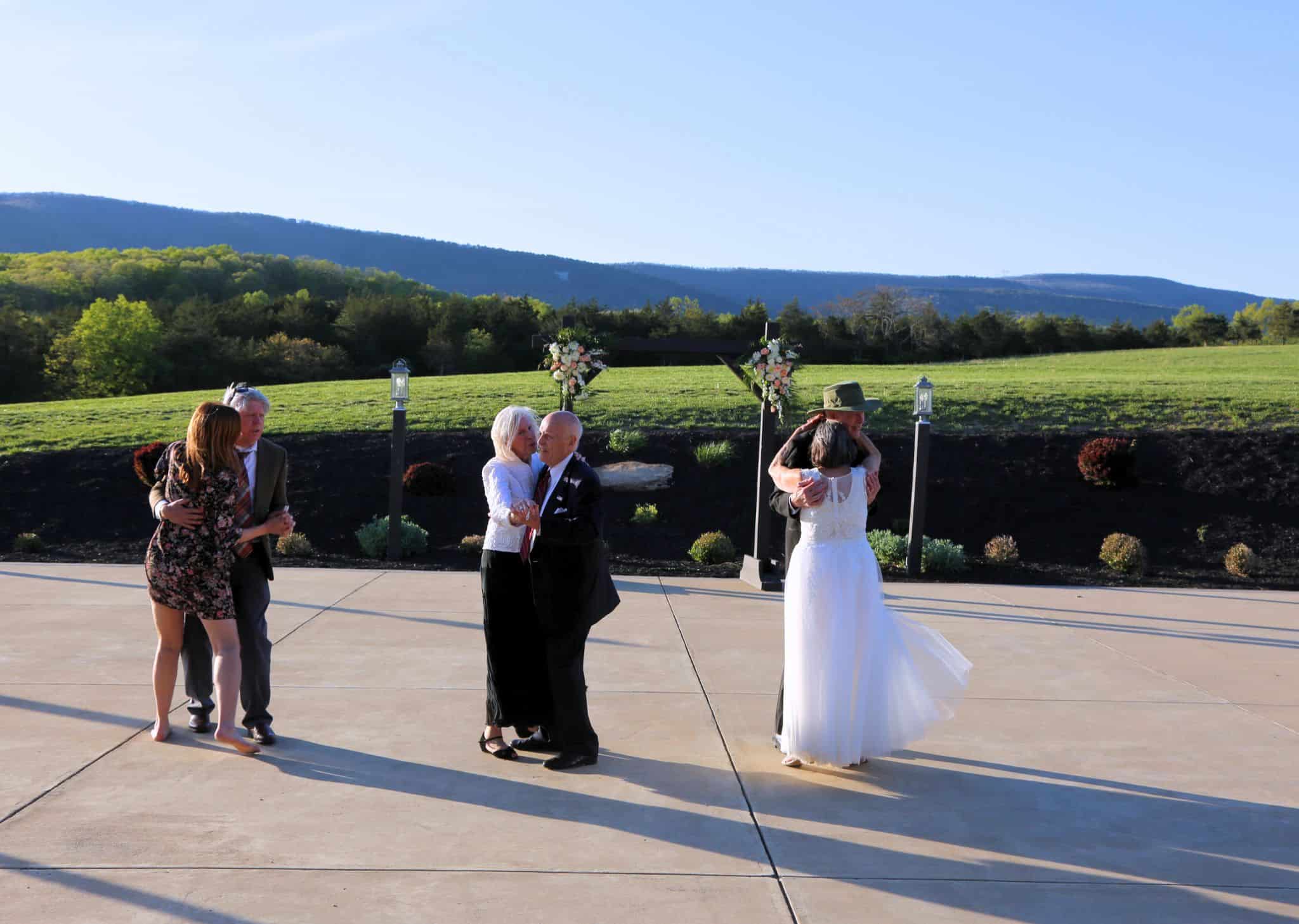 Multiple couples joyfully dancing on the patio during the later reception at Canaan Springs, with Blue Ridge Mountains in the backdrop, located in the Shenandoah Valley, Northern VA near Winchester, VA and the Winchester area