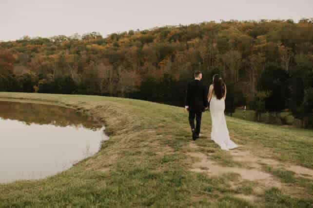 Bride and groom walking hand in hand beside the pond at Canaan Springs, a scenic farm wedding venue in Northern Virginia