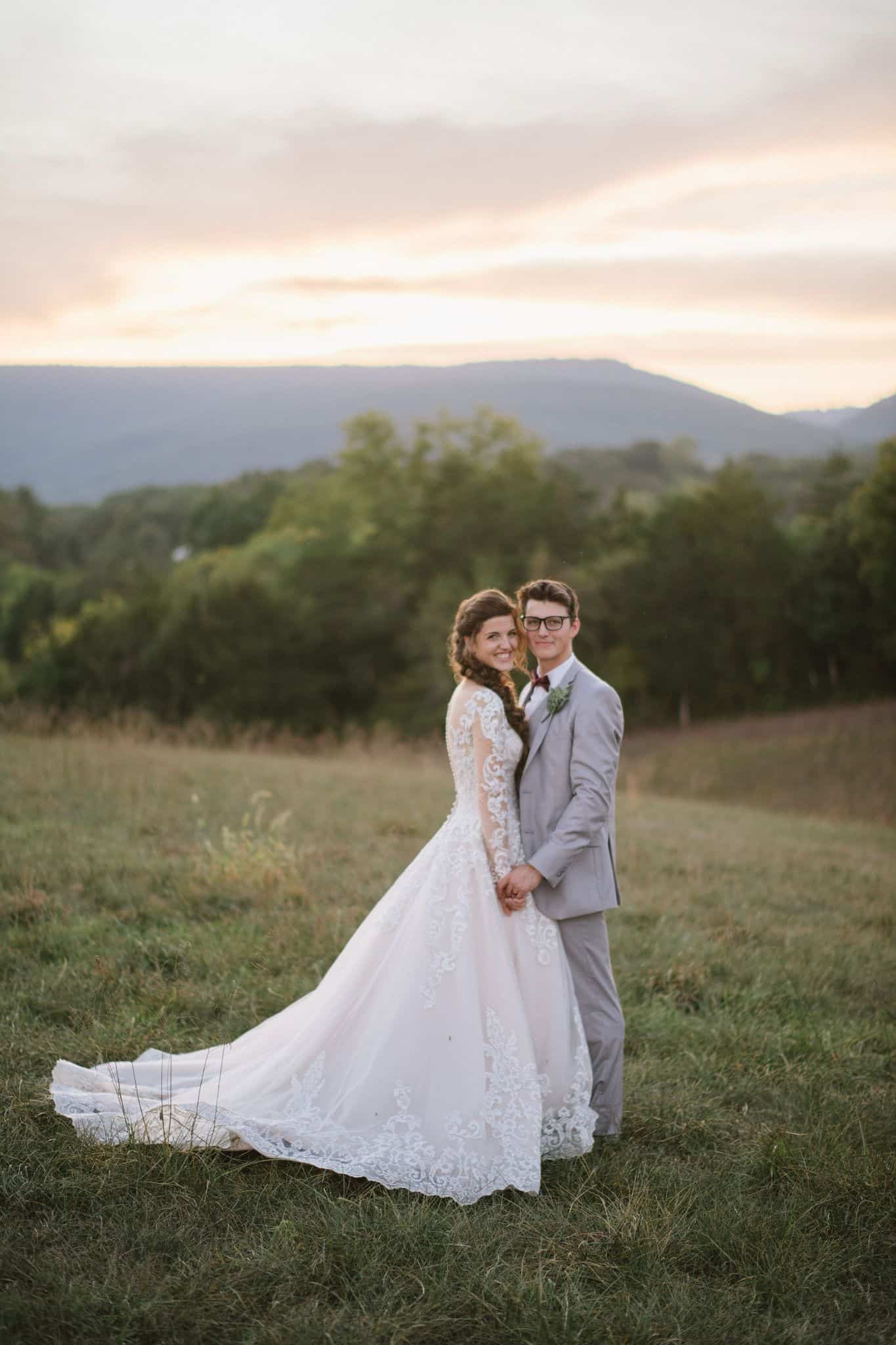 Just married couple smiling on a hilltop with the Blue Ridge Mountains and sunset in the background at Canaan Springs, a farm wedding venue in Northern Virginia