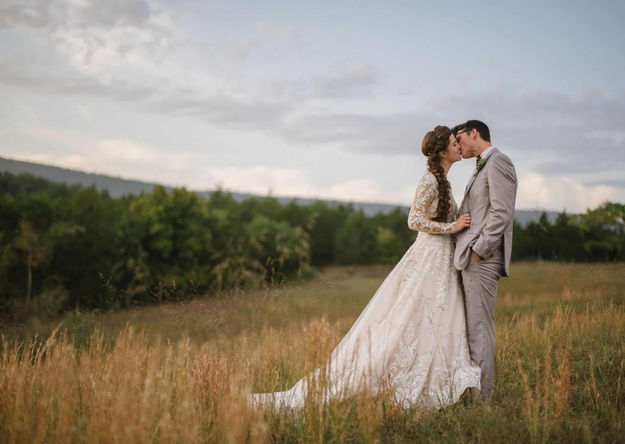 Just married couple kissing in golden fields with tall grass at Canaan Springs, a rustic Northern Virginia farm wedding venue near Winchester, VA