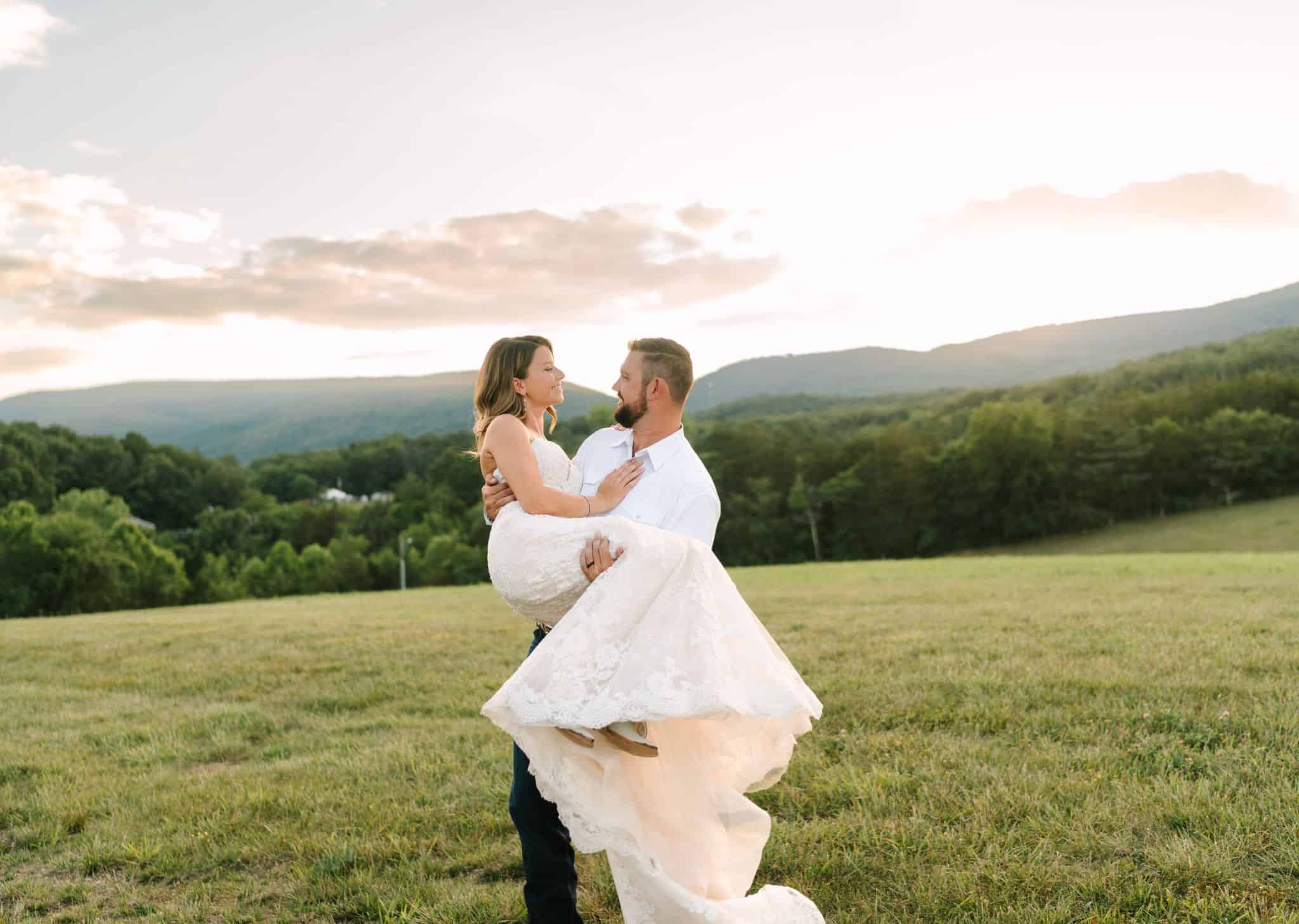 groom holding bride on hilltop with mountain views and gorgeous sky at Canaan Springs, a Northern Virginia farm wedding venue near Winchester, VA
