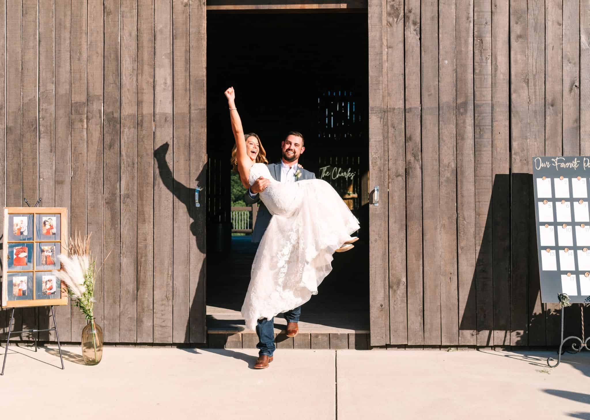 Just married couple with groom holding bride as they exit the barn doors at Canaan Springs, a rustic Northern Virginia farm wedding venue near Winchester, VA