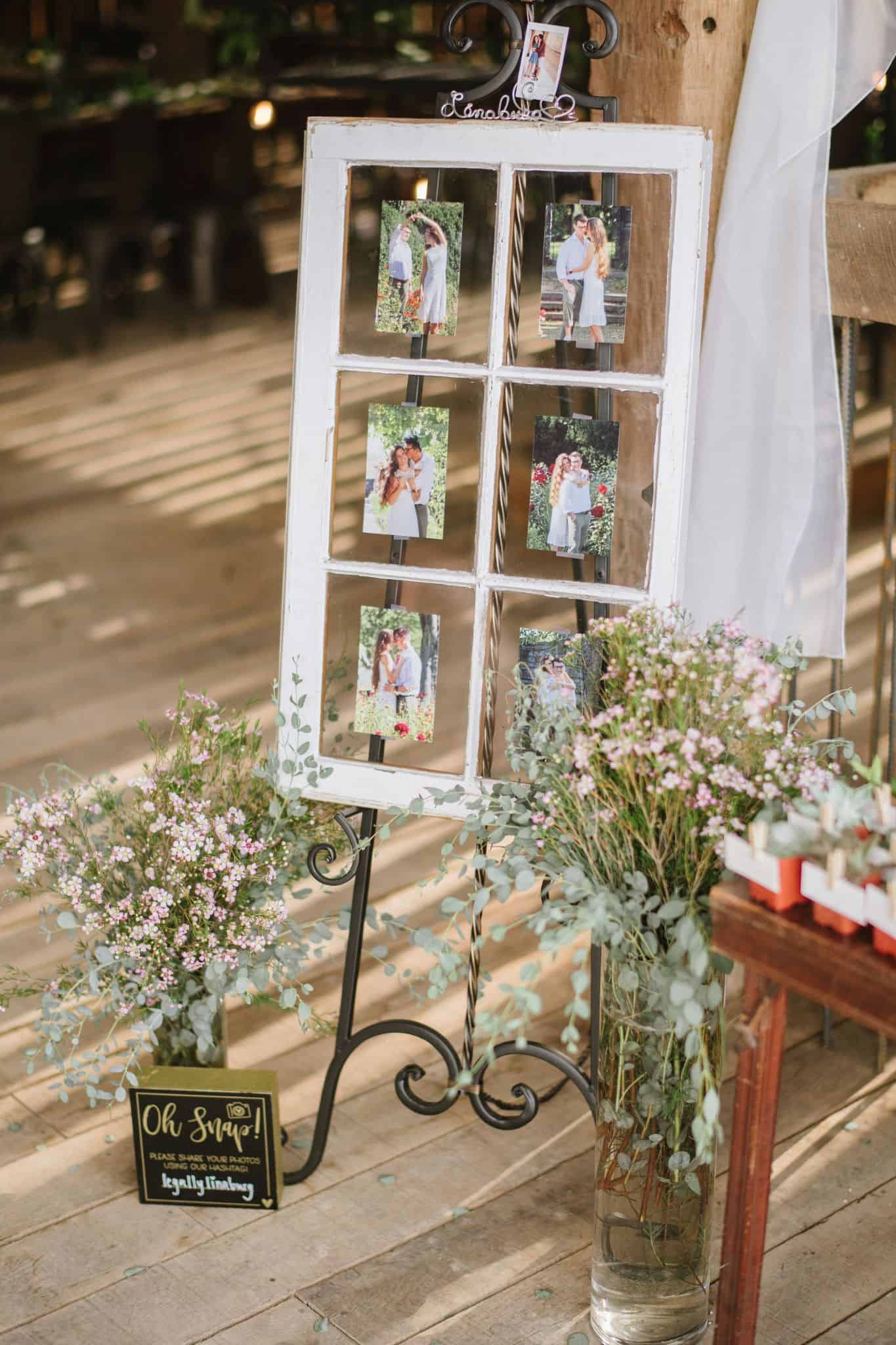 Vintage old window decorated with baby's breath and eucalyptus at the barn reception at Canaan Springs, displaying engagement photos of the couple at this Northern Virginia farm wedding venue
