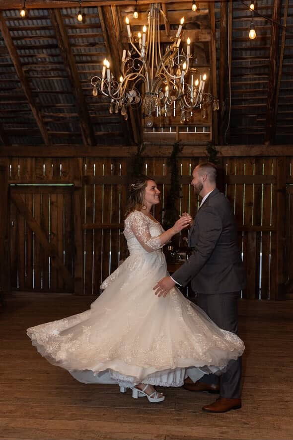 Bride and groom share their first dance in the rustic barn at Canaan Springs wedding venue in Northern Virginia, with her dress twirling under warm string lights