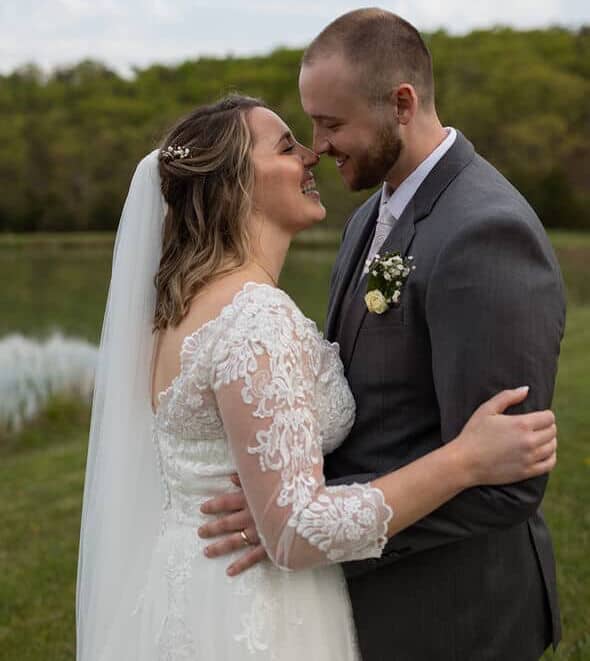 Close-up of bride and groom laughing and sharing a kiss by the pond at Canaan Springs, a romantic farm wedding venue in Northern Virginia