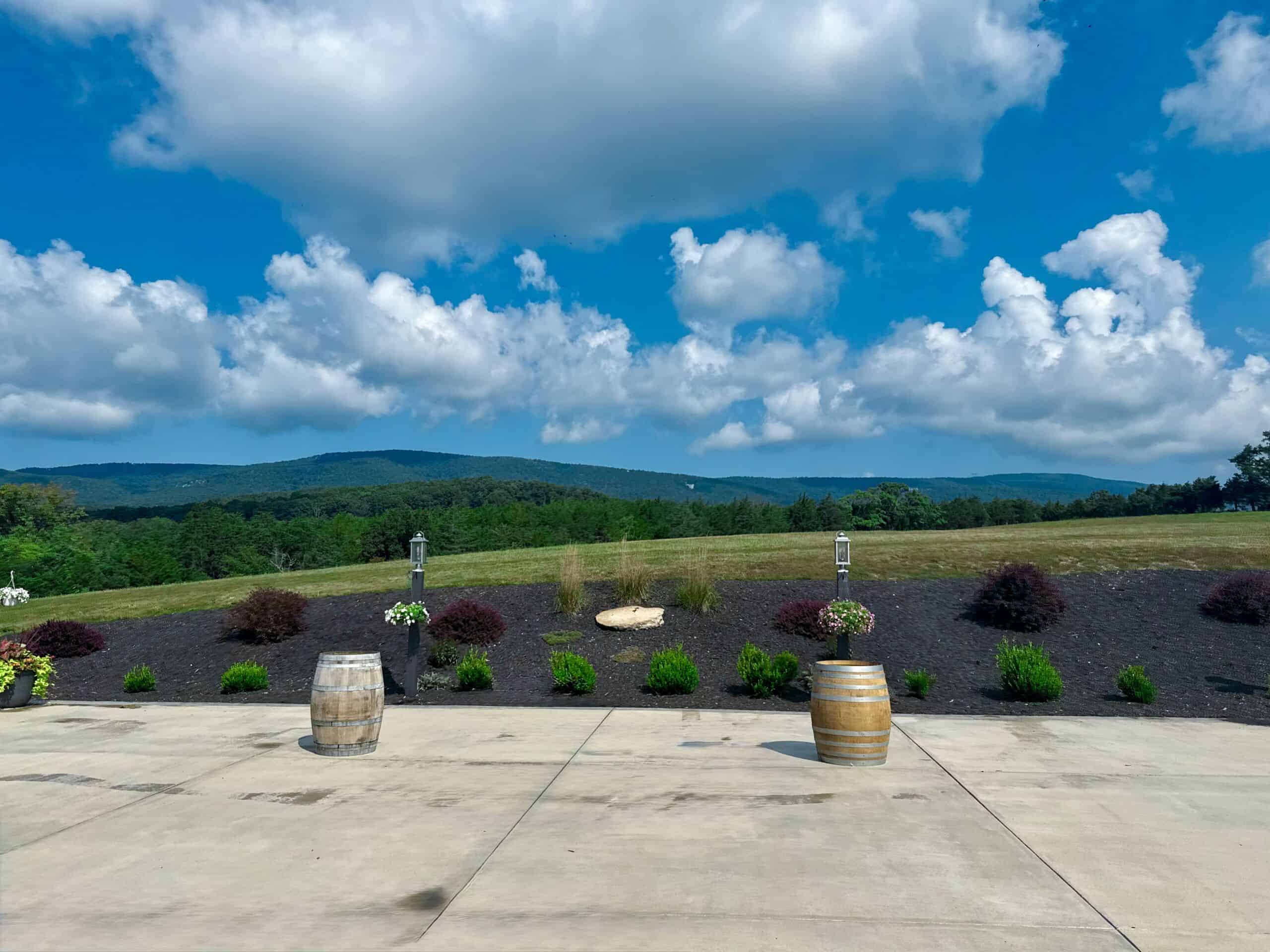 Whiskey barrels used as cocktail tables on the large patio at Canaan Springs overlooking the Blue Ridge Mountains during a wedding reception and cocktail hour