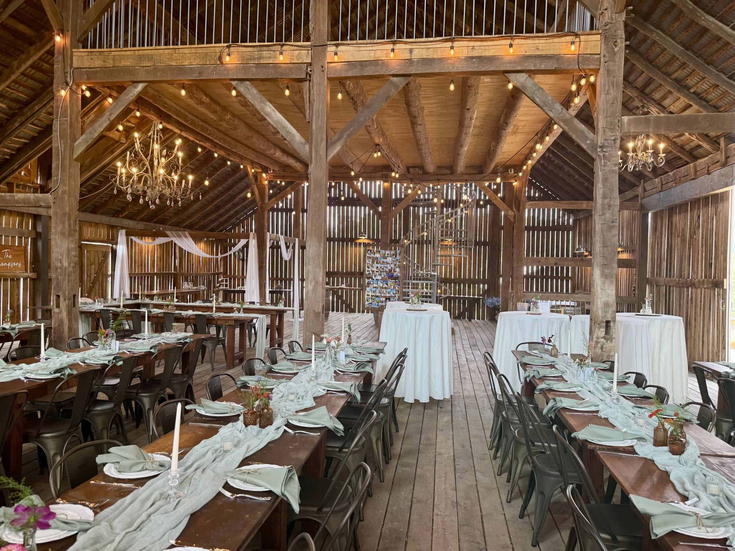 Canaan Springs barn wedding venue in Northern Virginia decorated with chandeliers, string lights, tablecloths, and white tulle draped on support posts