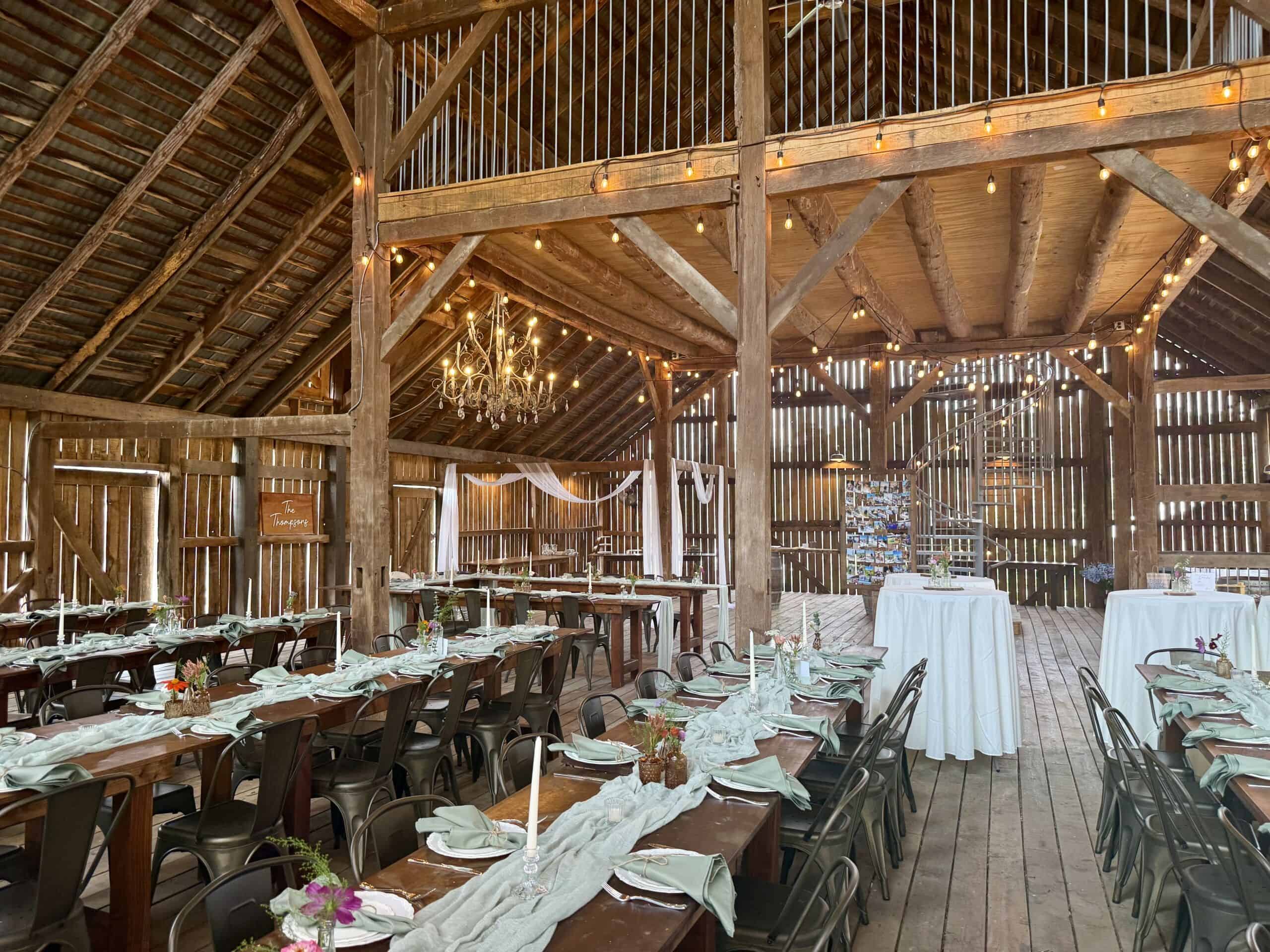 Barn wedding reception at Canaan Springs with chandelier lighting, white sashes, and handmade farm tables in Northern Virginia