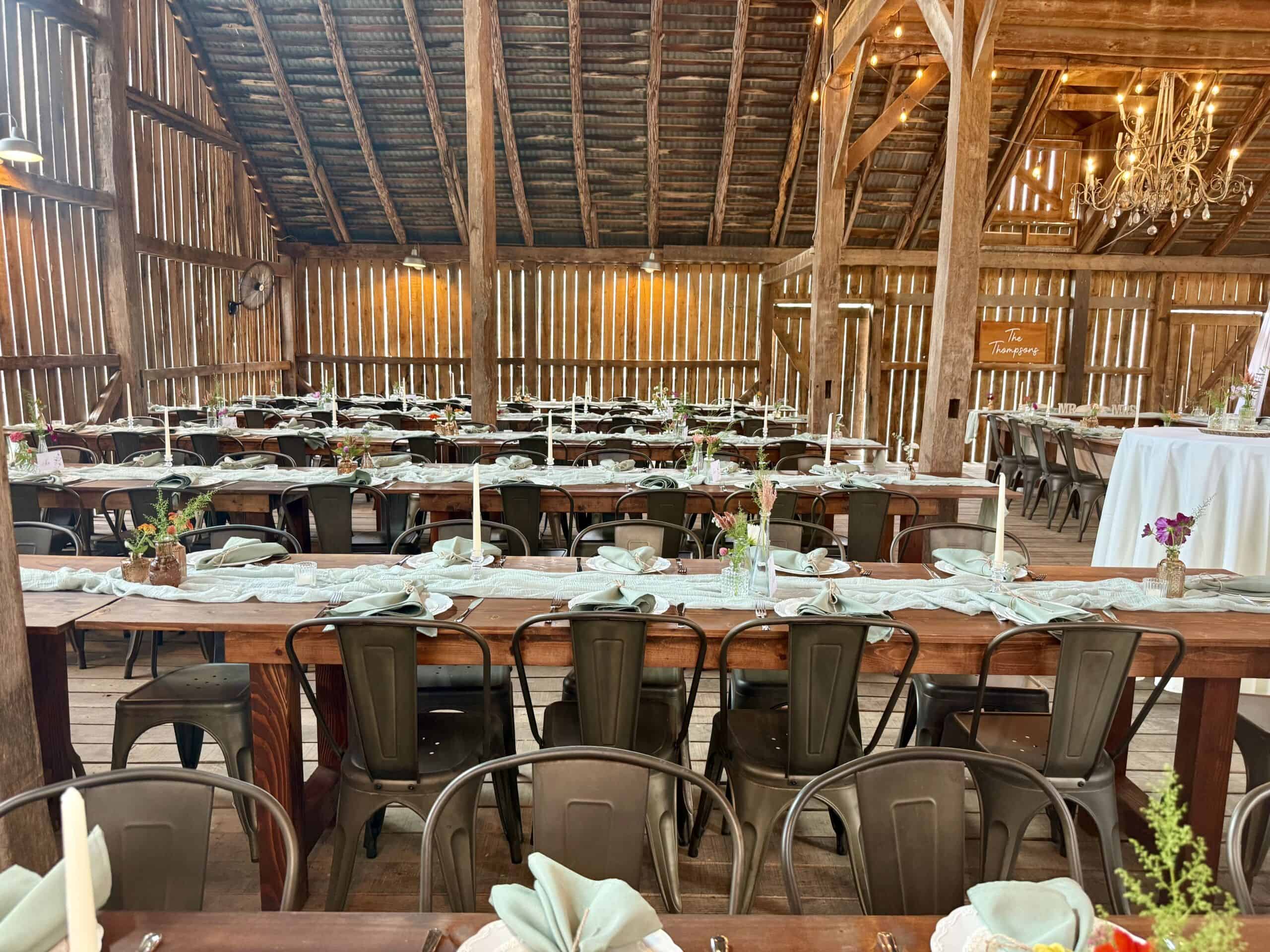 Close-up of long handmade farm tables decorated for a wedding reception inside the barn at Canaan Springs Northern Virginia wedding venue