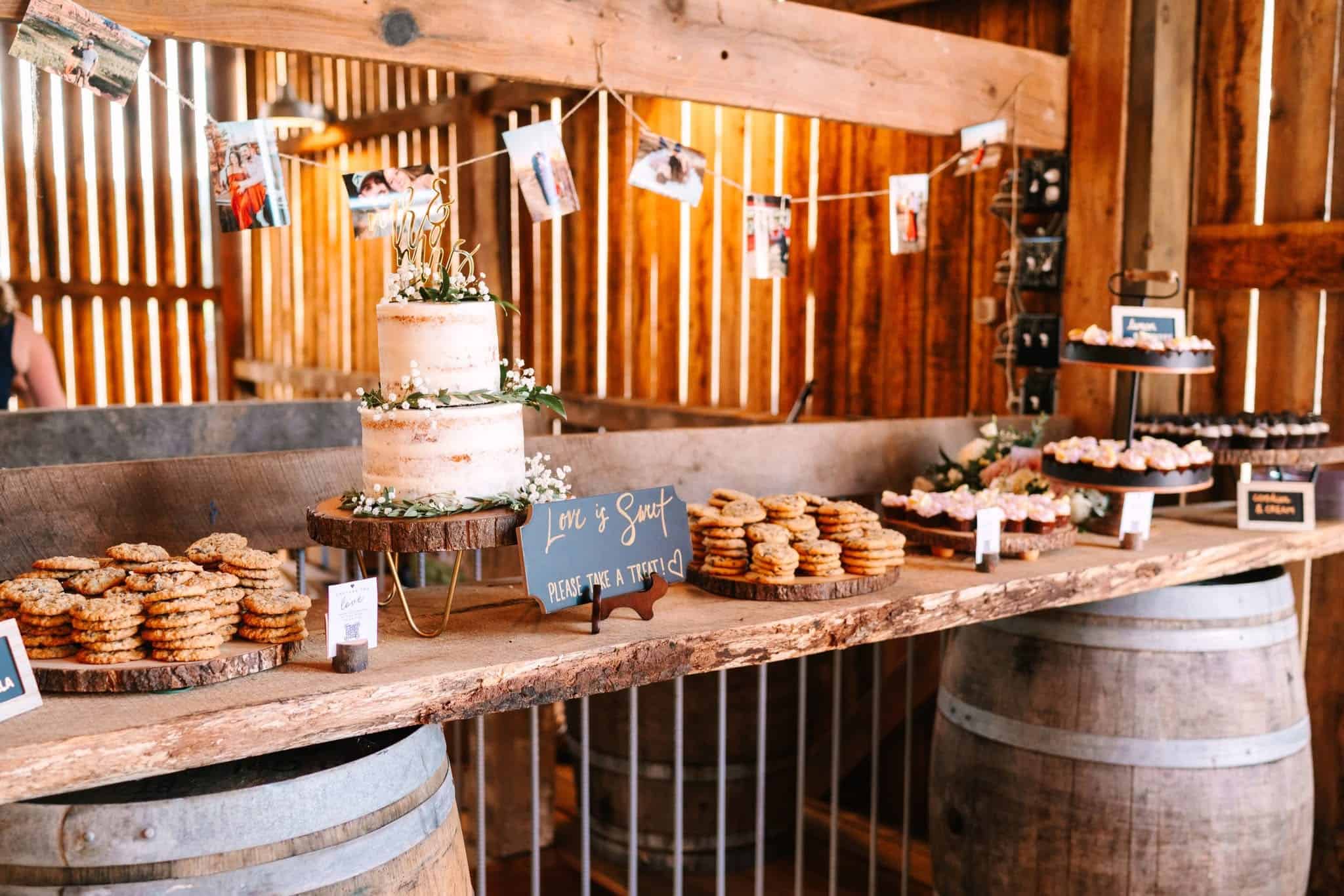 Rustic dessert bar displayed on whiskey barrels inside the barn at Canaan Springs wedding venue in Winchester Virginia