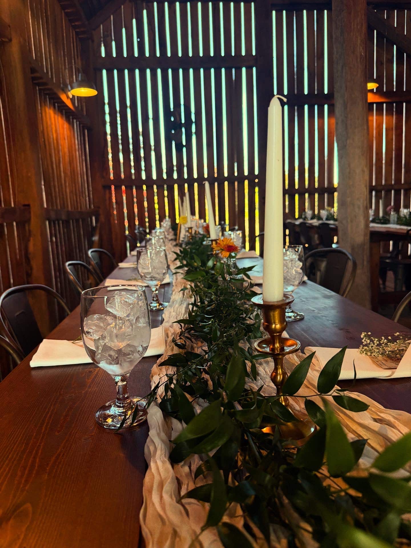 Farm tables set for a candlelit wedding reception inside the restored barn at Canaan Springs, a Northern Virginia barn wedding venue near Winchester, VA
