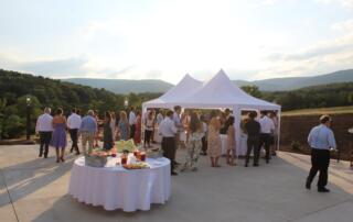 Guests mingle beneath a tent on the patio at Canaan Springs, a Northern Virginia barn wedding venue near Winchester, with scenic Blue Ridge Mountain views during cocktail hour.