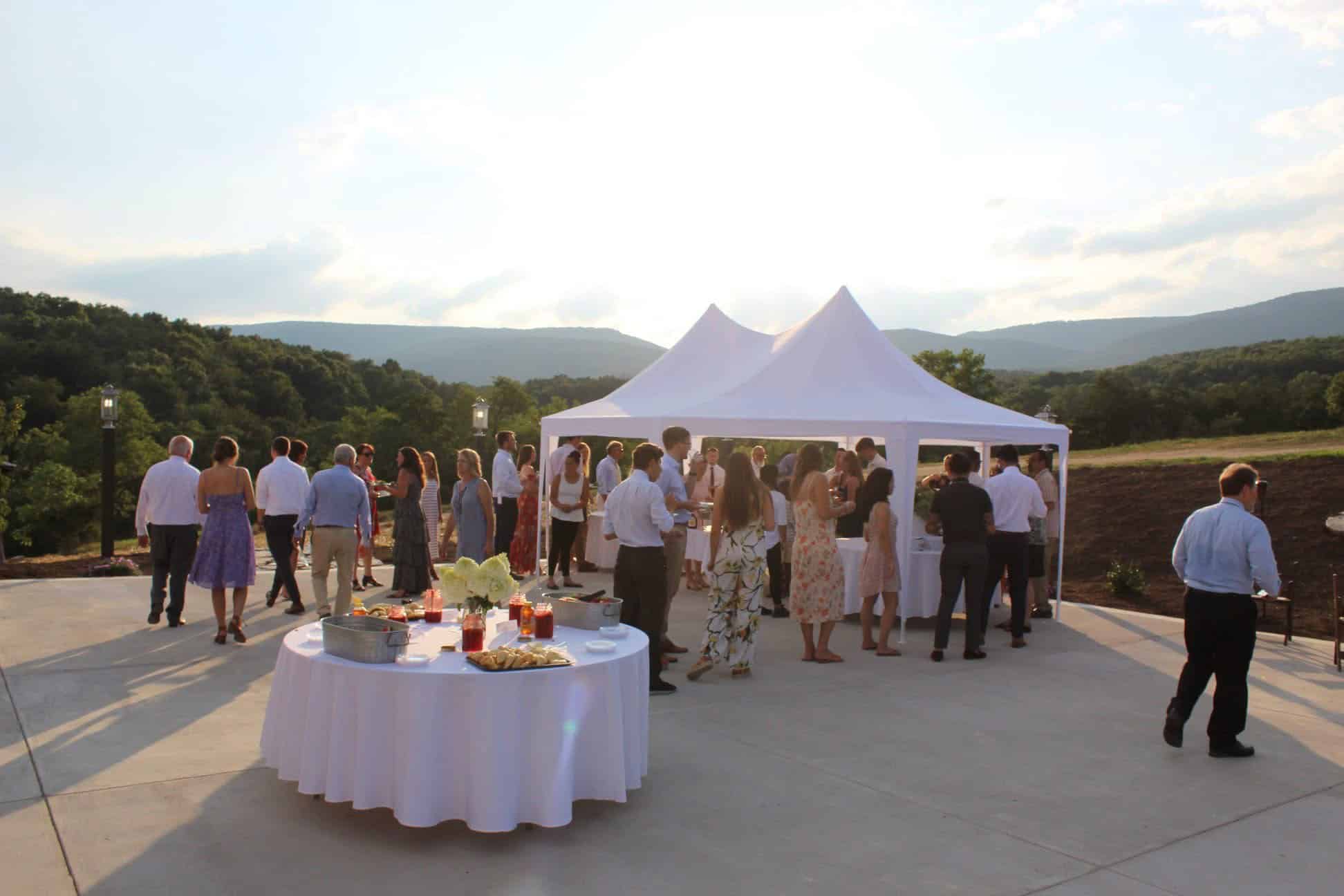 Guests mingle beneath a tent on the patio at Canaan Springs, a Northern Virginia barn wedding venue near Winchester, with scenic Blue Ridge Mountain views during cocktail hour.