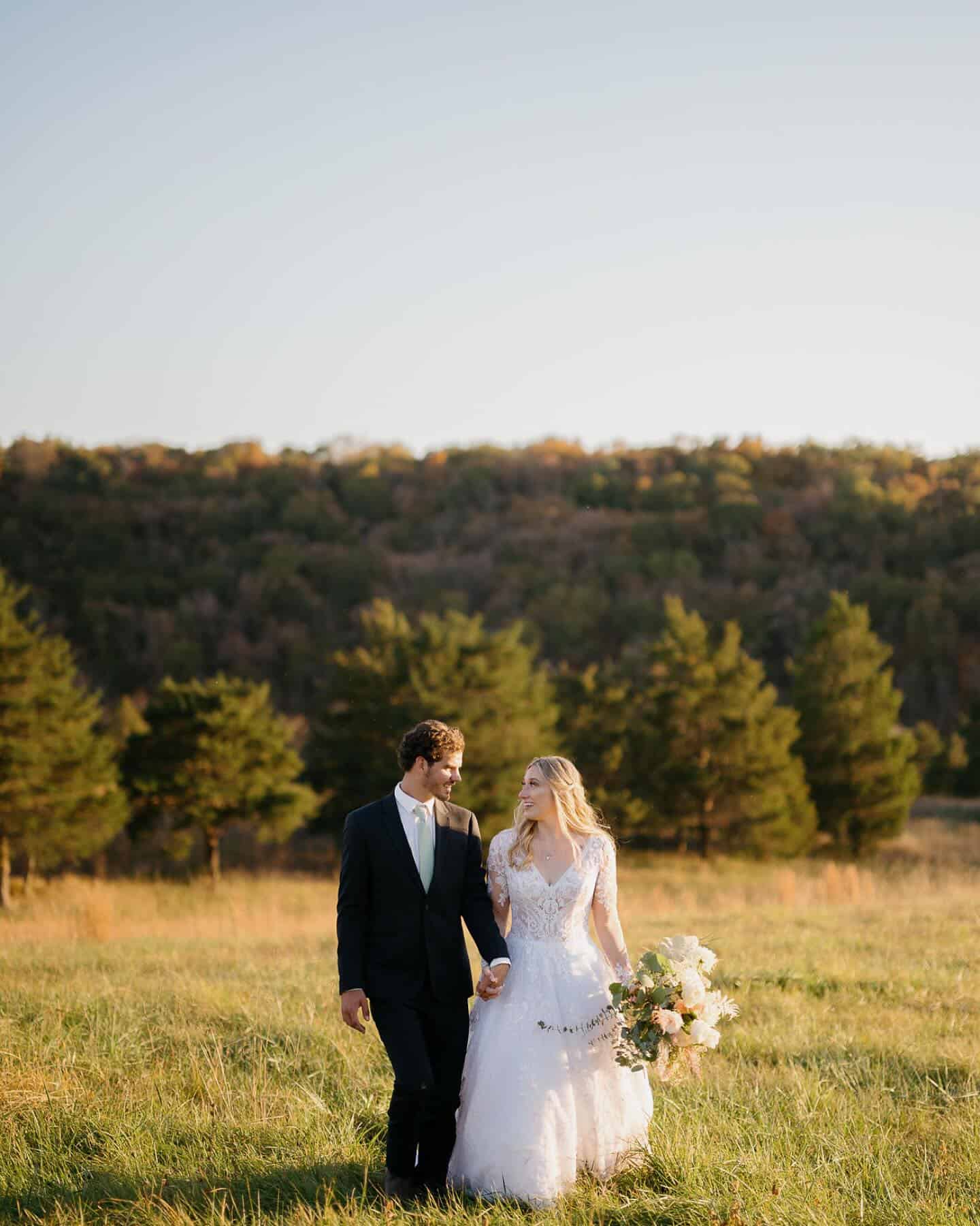 Just married couple walking through golden fields with mountain views at Canaan Springs, a Northern Virginia farm wedding venue near Winchester, Virginia