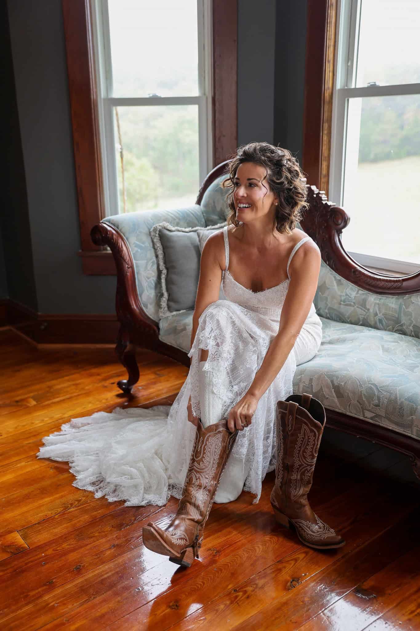 Bride in her wedding dress putting on cowboy boots inside the farmhouse at Canaan Springs, a Northern Virginia farm wedding venue near Winchester, VA