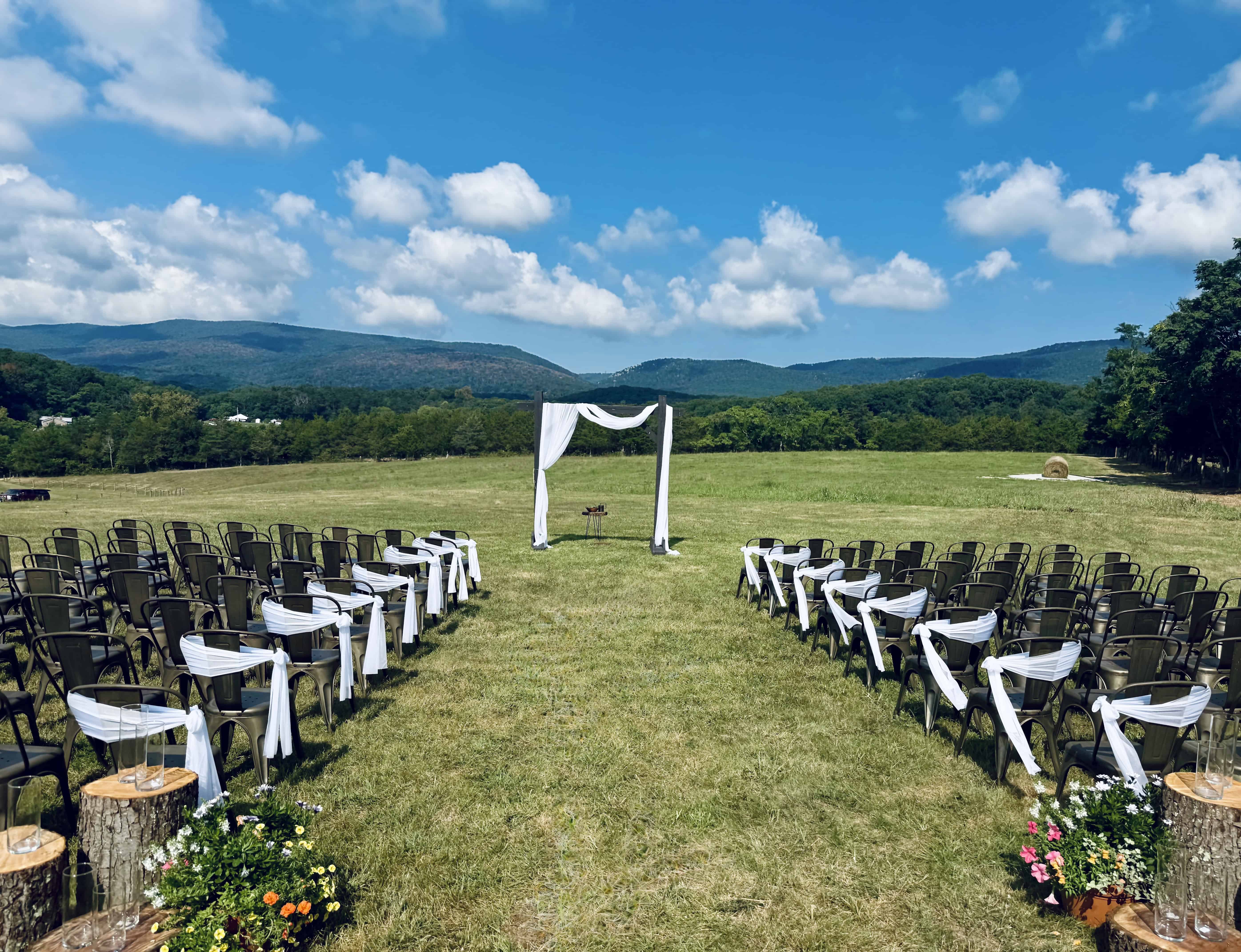Outdoor wedding ceremony with mountain backdrop at Canaan Springs, a Northern Virginia farm wedding venue near Winchester, featuring an elegant arbor and scenic countryside views