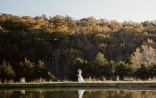 Just married couple reflected in a large pond at Canaan Springs Northern Virginia wedding venue near Winchester, Virginia, featuring expansive farm landscape and scenic water views.