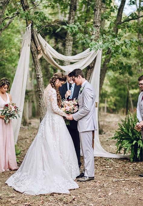 Couple standing at a wooded outdoor ceremony site at Canaan Springs, an upscale Northern VA wedding venue near Winchester with mature trees, natural landscape, and private ceremony setting